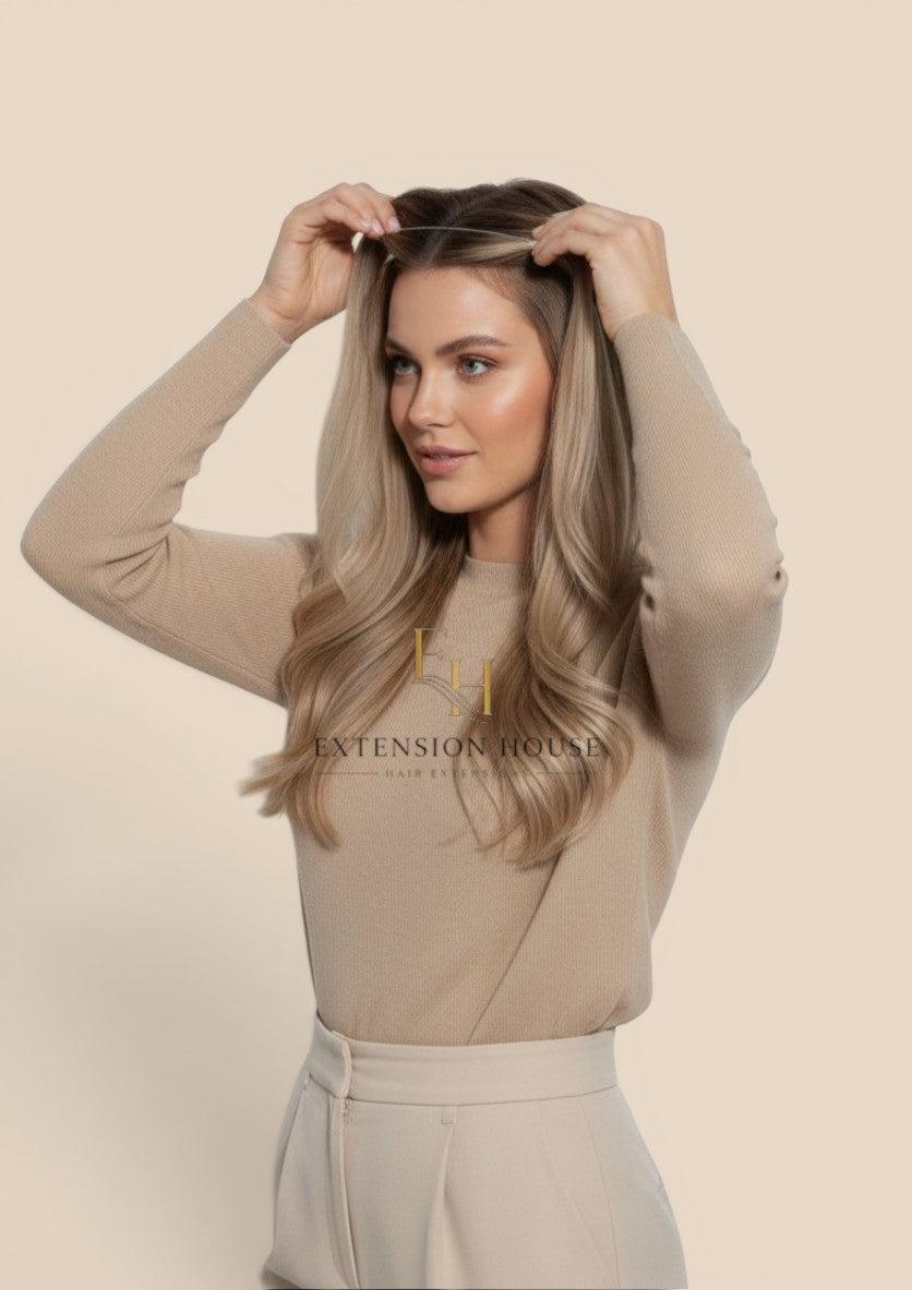 Extension house Halo Flip In Extensions in lichtblond met highlights, gedragen door een model met natuurlijk haar.