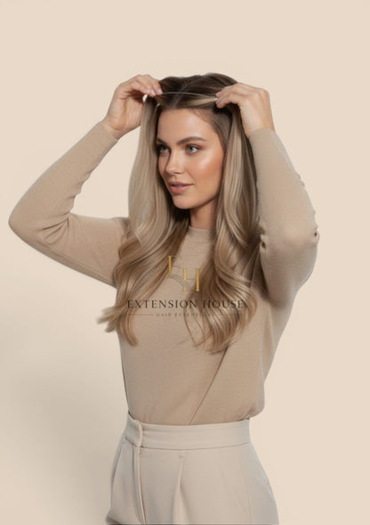 Extension house Halo Flip In Extensions in lichtblond met highlights, gedragen door een model met natuurlijk haar.