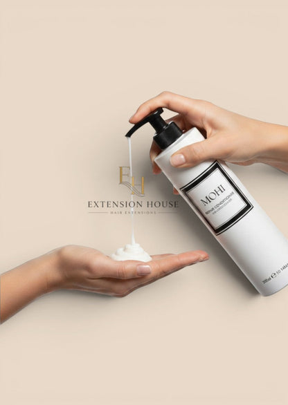 Extension house MOHI herstellende conditioner in witte pompflacon die rijke witte crème in een handpalm doseert.